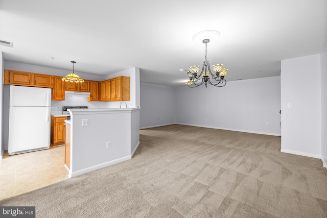 kitchen featuring under cabinet range hood, light countertops, freestanding refrigerator, light colored carpet, and a notable chandelier