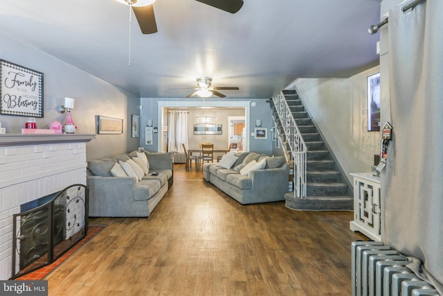 living room featuring a brick fireplace, radiator heating unit, dark hardwood / wood-style floors, and ceiling fan