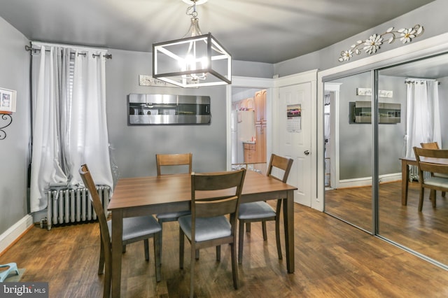 dining room featuring radiator, dark wood-type flooring, and a chandelier