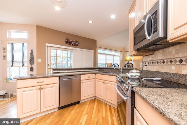 kitchen with light stone counters, plenty of natural light, stainless steel appliances, and kitchen peninsula