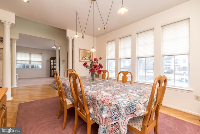 dining room featuring a healthy amount of sunlight, light hardwood / wood-style floors, and decorative columns