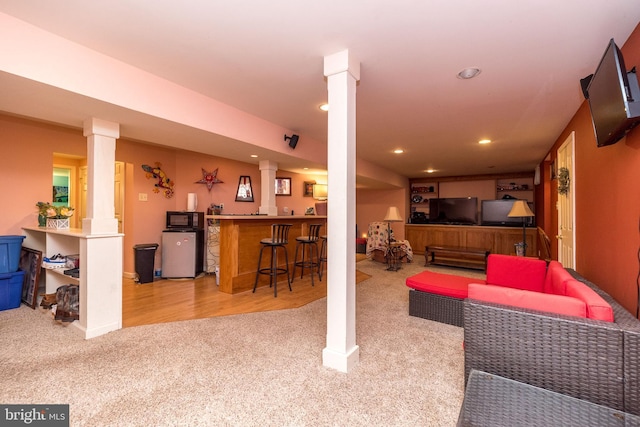 carpeted living room featuring indoor bar and decorative columns