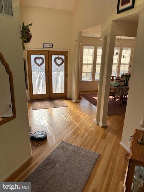 entrance foyer featuring lofted ceiling, decorative columns, french doors, and light wood-type flooring