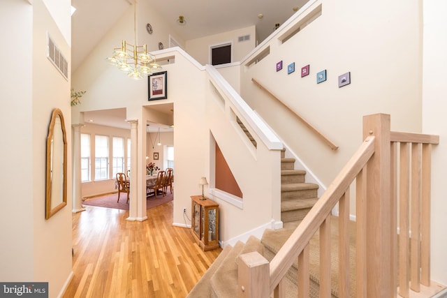 stairs with hardwood / wood-style floors, a notable chandelier, and a high ceiling