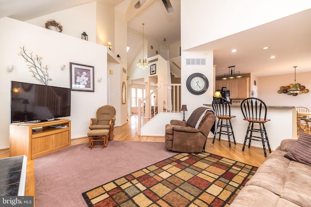 living room featuring a notable chandelier, wood-type flooring, and high vaulted ceiling