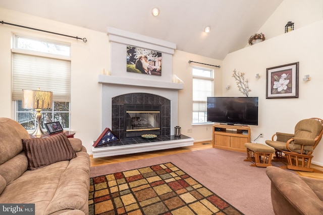 living room featuring lofted ceiling, carpet flooring, and a tile fireplace