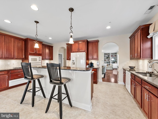 kitchen with white appliances, a center island, sink, and hanging light fixtures