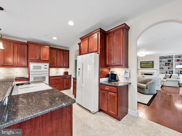 kitchen featuring white appliances, dark stone counters, and decorative backsplash