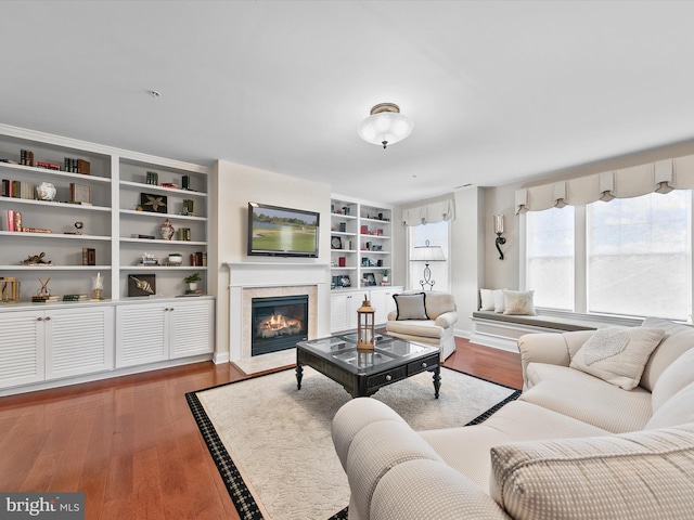 living room featuring hardwood / wood-style floors, a high end fireplace, and built in shelves