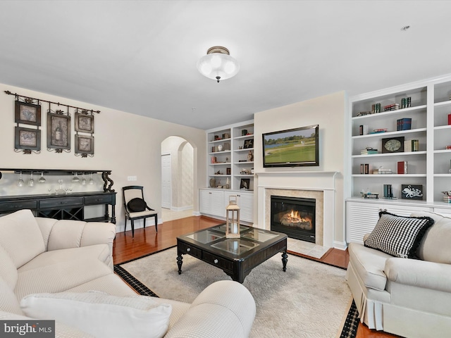 living room featuring hardwood / wood-style flooring, a high end fireplace, and built in shelves