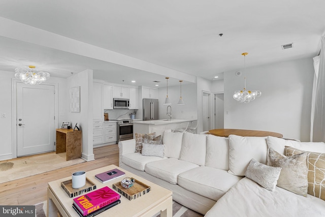 living room featuring recessed lighting, visible vents, light wood finished floors, and an inviting chandelier