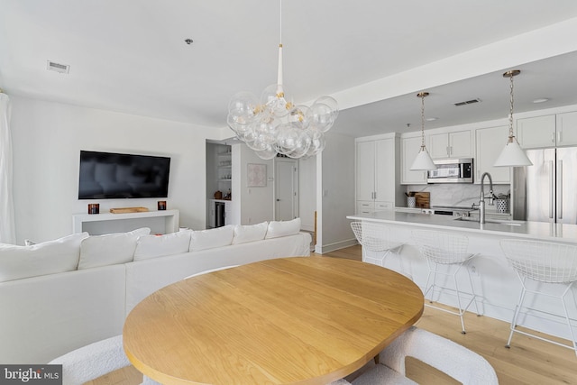 dining room featuring light wood-style floors, visible vents, and a chandelier