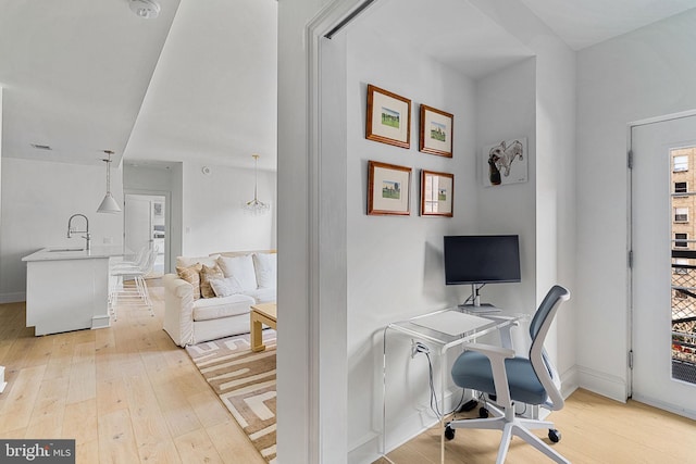 office space with baseboards, a sink, and light wood-style floors