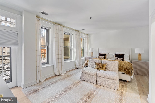 bedroom featuring light wood-style floors, visible vents, and baseboards