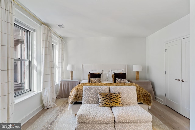 bedroom featuring multiple windows, light wood-type flooring, visible vents, and baseboards