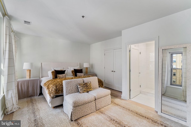 bedroom featuring a closet, visible vents, and ensuite bath