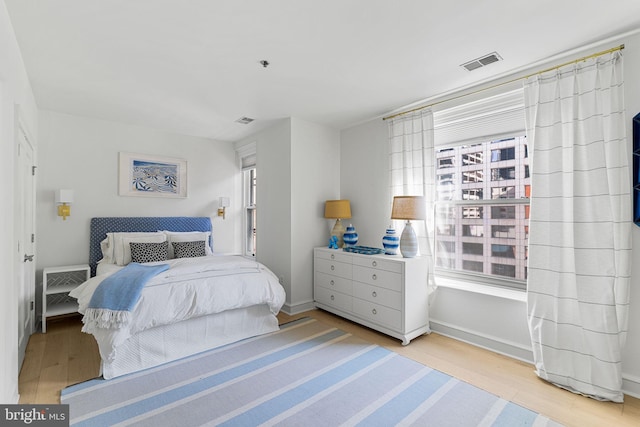 bedroom with light wood-type flooring, visible vents, and baseboards