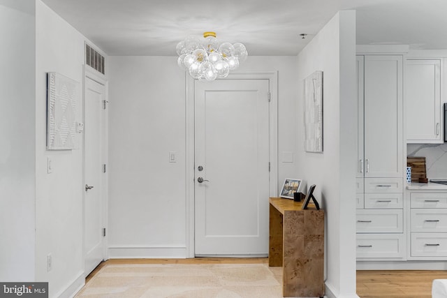 entryway with a chandelier, light wood-type flooring, and visible vents