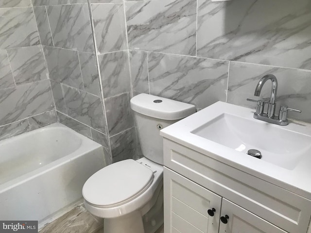 bathroom with vanity, toilet, tile walls, and a tub