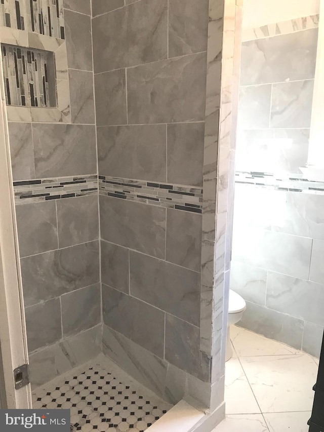 bathroom featuring a tile shower and toilet