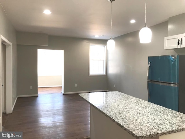 kitchen with white cabinetry, dark hardwood / wood-style floors, a center island, light stone countertops, and decorative light fixtures