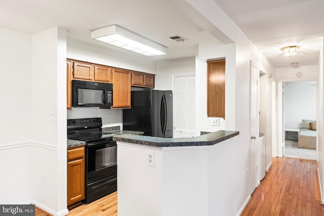 6913 Victoria, Alexandria, VA 22310 - kitchen featuring dark countertops, visible vents, light wood-style floors, brown cabinets, and black appliances