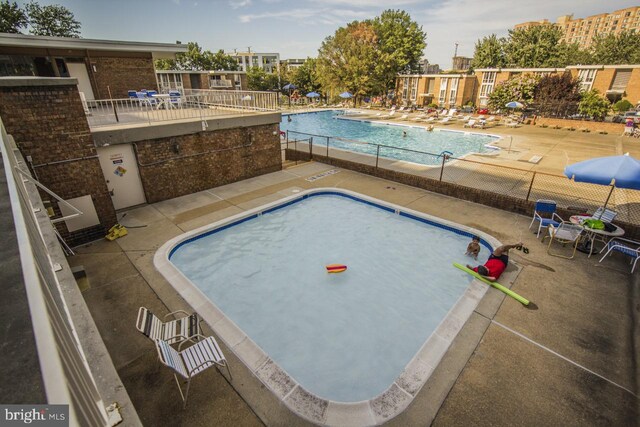 community pool with a patio area and fence