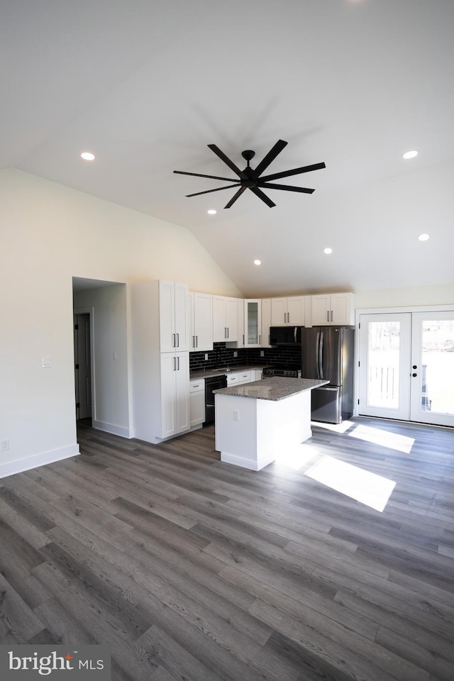 kitchen with vaulted ceiling, a kitchen island, black dishwasher, white cabinets, and stainless steel fridge