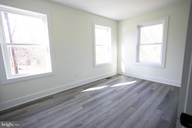 spare room with plenty of natural light and dark hardwood / wood-style flooring