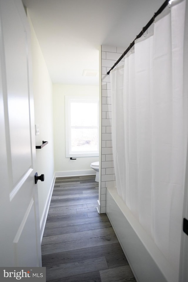 bathroom featuring hardwood / wood-style flooring, toilet, and shower / tub combo