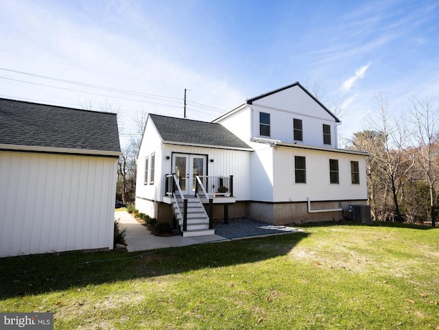 rear view of house featuring central AC unit, a lawn, and french doors