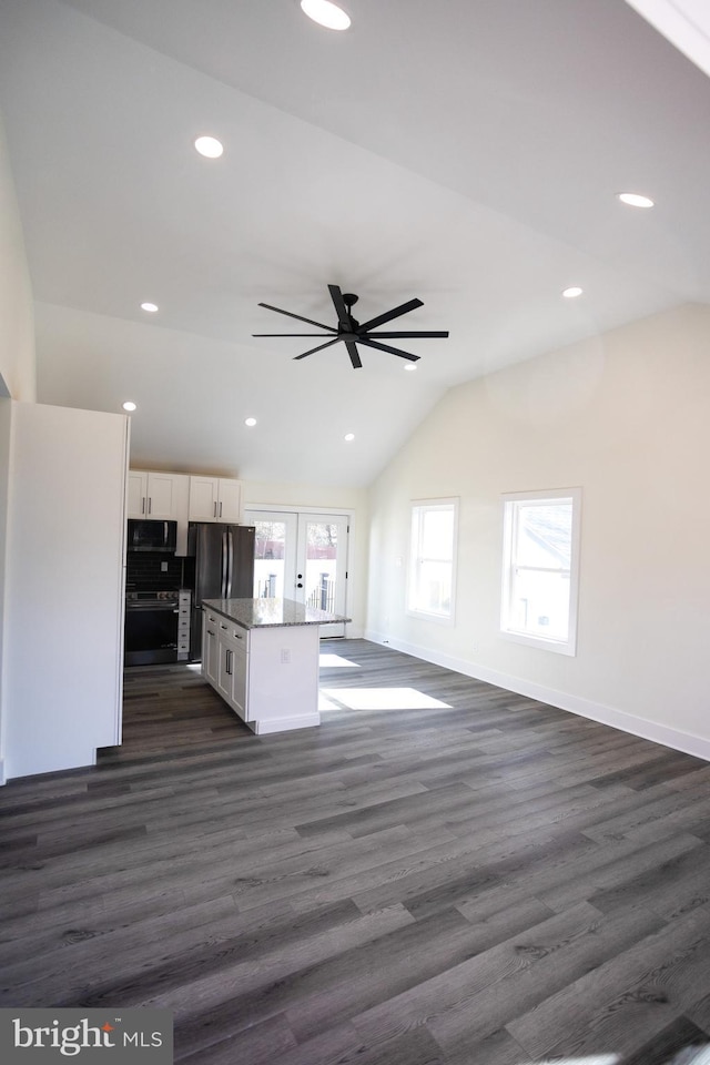 kitchen with vaulted ceiling, white cabinetry, a center island, light stone counters, and stainless steel appliances