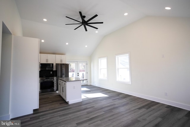 kitchen with lofted ceiling, white cabinetry, a kitchen island, stainless steel appliances, and light stone countertops