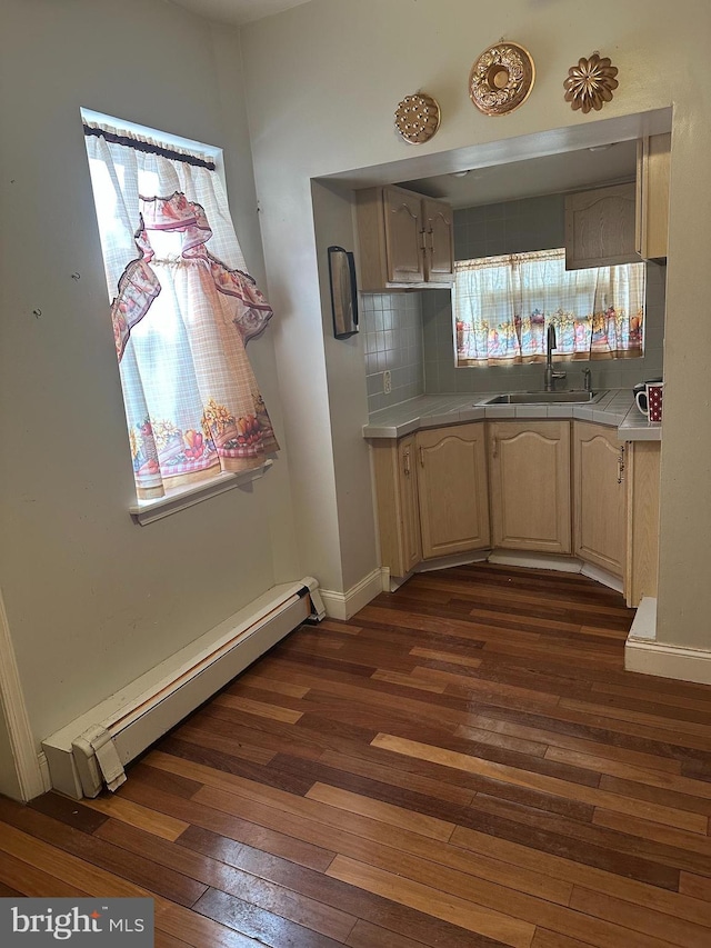 kitchen with sink, decorative backsplash, baseboard heating, dark wood-type flooring, and light brown cabinets