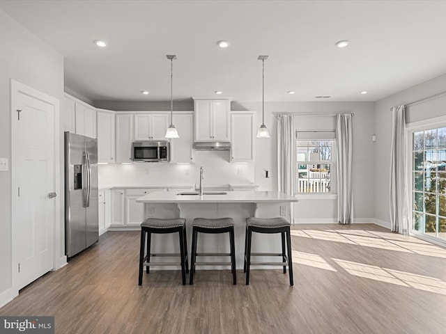 kitchen with white cabinetry, an island with sink, sink, hanging light fixtures, and stainless steel appliances