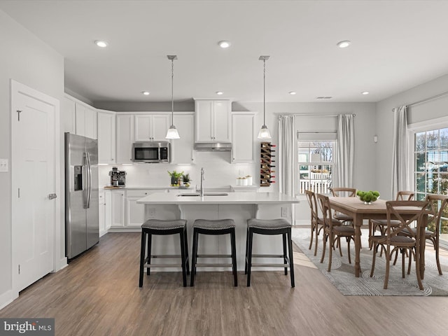 kitchen with appliances with stainless steel finishes, pendant lighting, sink, white cabinets, and dark wood-type flooring