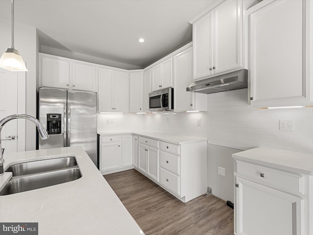 kitchen featuring sink, white cabinetry, wood-type flooring, appliances with stainless steel finishes, and pendant lighting