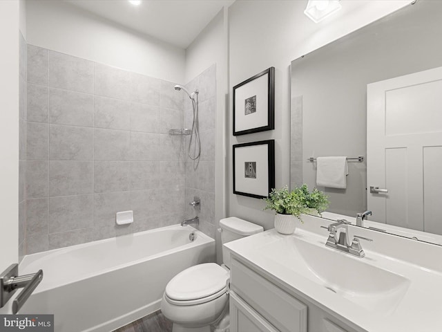 full bathroom featuring tiled shower / bath, vanity, and toilet