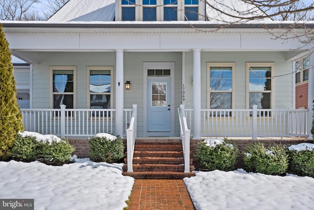 snow covered property entrance featuring a porch