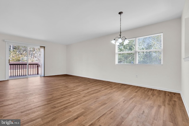 spare room with hardwood / wood-style flooring and a notable chandelier