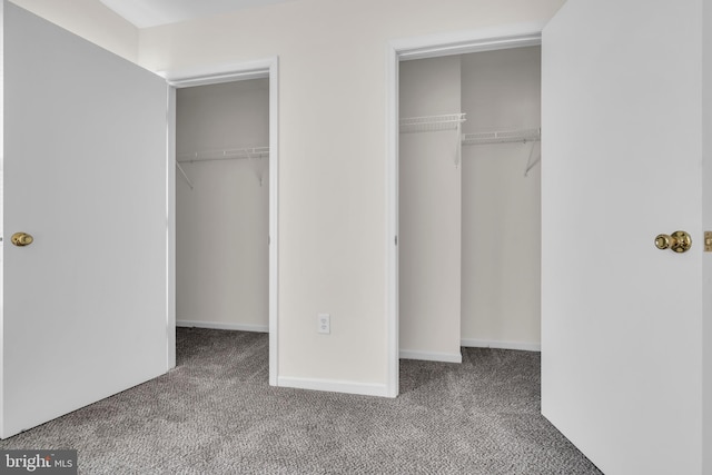 unfurnished bedroom featuring multiple closets and light colored carpet