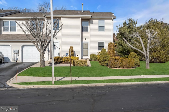 view of property with a garage and a front lawn