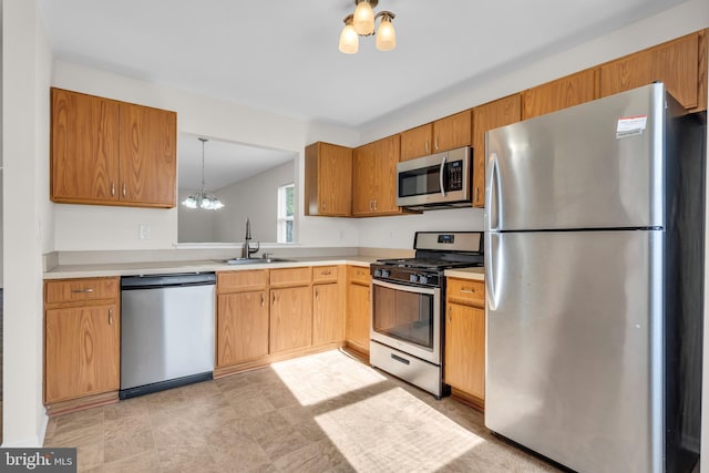 kitchen with pendant lighting, sink, an inviting chandelier, and appliances with stainless steel finishes