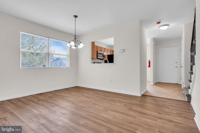 unfurnished dining area featuring an inviting chandelier and light hardwood / wood-style floors