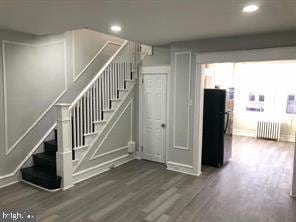 stairs featuring hardwood / wood-style flooring and radiator heating unit