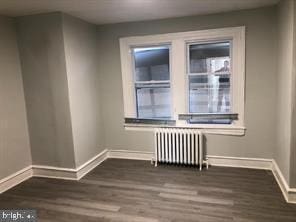 unfurnished room with radiator and dark hardwood / wood-style floors