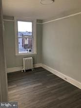 spare room with dark hardwood / wood-style flooring and radiator