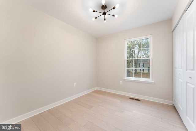 unfurnished bedroom with a closet, a chandelier, and light wood-type flooring