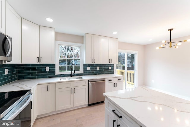 kitchen with white cabinetry, sink, light stone counters, and appliances with stainless steel finishes