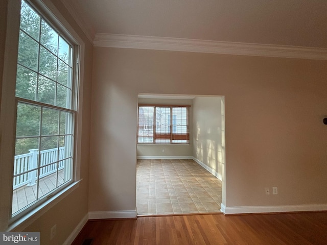 unfurnished room featuring light wood-type flooring, baseboards, and crown molding